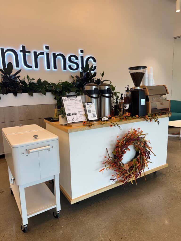 Coffee bar with brewing equipment and decorative wreath.