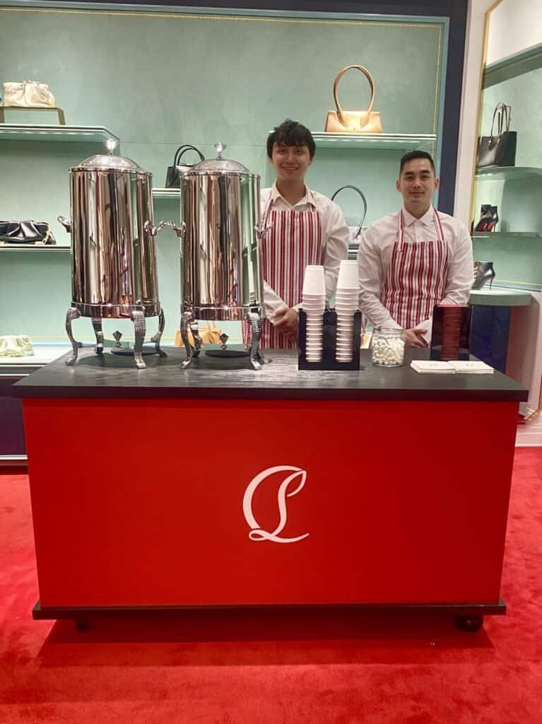 Coffee serving station with two large stainless steel dispensers and two baristas.