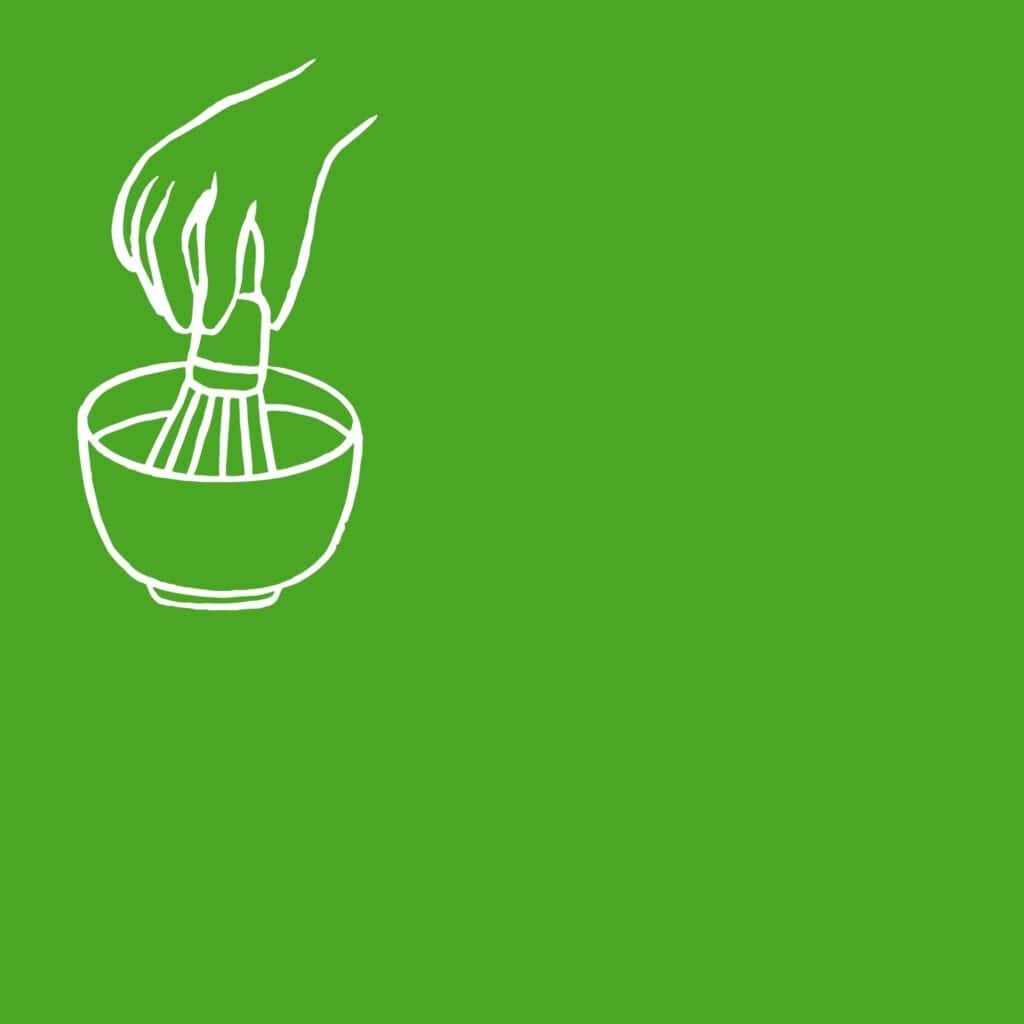 Hand whisking coffee in a bowl on a green background.