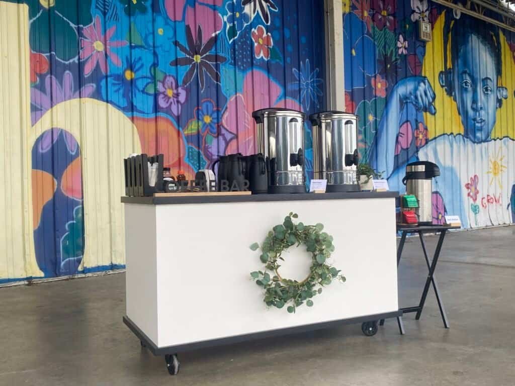 Mobile coffee bar with colorful mural background at Sunny Cups Coffee.