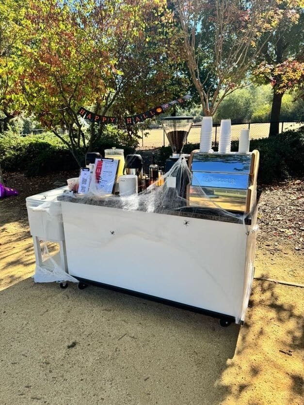 Outdoor coffee cart serving hot beverages with Halloween decorations.