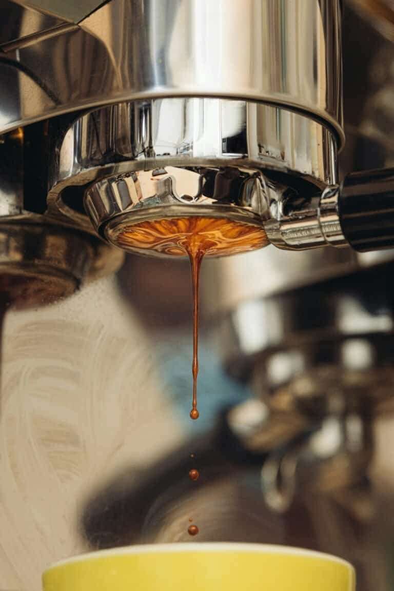 Close-up of espresso shot dripping from a professional coffee machine spout.