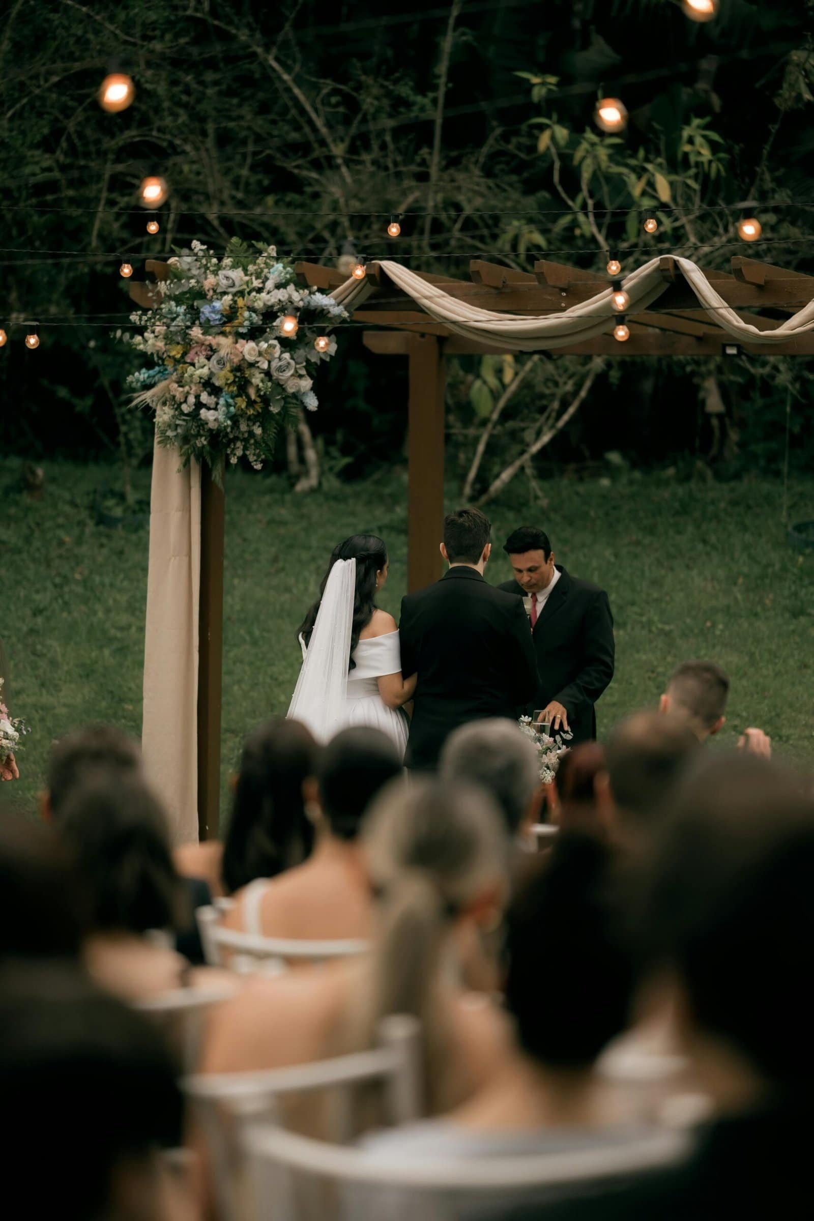 Outdoor wedding ceremony with string lights and floral decor at Sunny Cups Coffee.